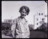 Nita Carson standing on a street smiling, Los Angeles, 1925