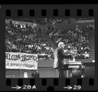 Dr. Benjamin Spock at podium during UCLA anti-war rally at Pauley Pavilion, 1968