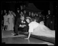 Mickey Rooney watching Judy Garland put handprint in cement at Grauman's Theatre during "Babes in Arms" film premiere, Hollywood (Los Angeles), 1939