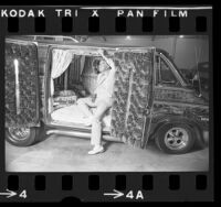 Man inspecting the crushed velvet interior of a custom conversion van in Los Angeles, Calif., 1975