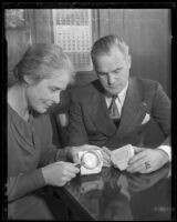 Los Angeles Park Commission president Mabel V. Socha and Deputy Chief of Police Homer Cross examining counterfeiting equipment, [Los Angeles], 1935