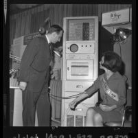 Miss Los Angeles Industrial Fair being examined by the Burton Electro-Medical physiological monitor at Industrial Fair and Congress, 1964