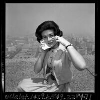 Jo Jeanne Angeloff rubbing eyes from effects of smog atop the Occidental Center building in Los Angeles, Calif., 1965