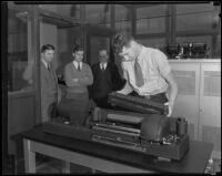 Three men watch as another man holds part of a Wirephoto machine, Los Angeles, 1935