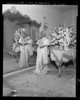 Actress Mae West posing in front of mirror for promotion of her "It Ain't History, It's Herstory" television series, 1953