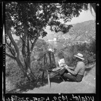 Frank W. McElroy painting on trail along cliff overlooking Avalon, Catalina Island, Calif., 1964