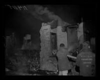 Firefighters combat smoldering ruins of Fountain of the World headquarters after a bomb destroyed the building in Box Canyon, near Simi Valley, 1958