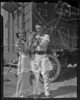 Man and woman hold a lion cub n front of an Al G. Barnes Wild Animal Circus car, Los Angeles, 1936