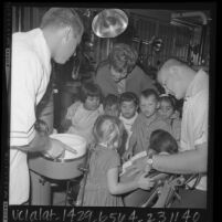 Youngsters watching Olympian and USC dental student, Dallas Long conduct dental examine, Los Angeles, Calif., 1965