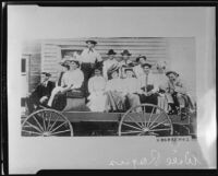 Group portrait of Will Rogers seated in a wagon with a group of men and women, circa 1900-1915