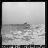 Lone male surfer riding a wave at Leo Carrillo Beach, Malibu, 1964