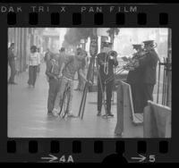 Boy on bicycle putting donation into kettle as four-piece Salvation Army brass band plays in Hollywood, Calif., 1971