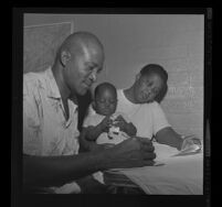 Peola Denham works on family budget with wife, Fannie, and son, Charles, 1962