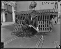 Inspector holds up metal rod meant to derail street car, Los Angeles, 1934