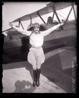 Aviatrix Ruth Elder with arms outstretched in front of her plane, Los Angeles, circa 1927