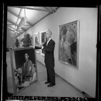 Artist Norman Rockwell standing amongst his paintings at exhibit at Municipal Art Gallery at Barnsdall Park, Los Angeles, 1965