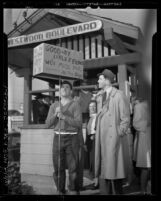 Actor Jimmy Stewart induction in United States Army; standing at Westwood train depot with man holding sign "good-by little fellows", 1941