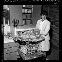 Charlotte H. Pownell in kitchen unveiling a salmon and vegetables cooked in a dishwasher, Calif., 1970