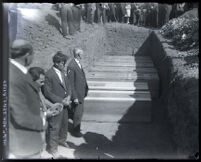 Seven coffins containing victims of St. Francis Dam failure lying in large grave surrounded by people, Santa Clara Valley (Calif.), 1928