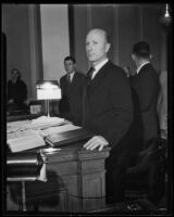 William H. Neblett, standing behind a paper-covered table, 1932