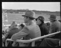 Actor Clark Gable and Ria Langham Gable in audience at outdoor event, 1930s