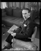 Architect Richard J. Neutra holding photograph of Beard House and smoking pipe, Los Angeles, 1935