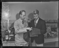 Murder suspect Fred Stettler holds his stained pants in front of chemist Ray Pinker, Los Angeles, 1936