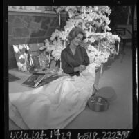 California's Junior Miss of 1963-64, Kim Carnes seated, sewing on gown she will wear in the Rose Parade