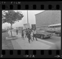 Protesters holding signs in front of the Century Plaza Hotel before Pres. Johnson's visit. 1967