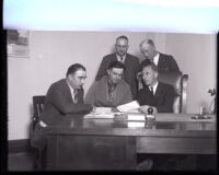 Deputy Buron Fitts seated with at a desk with Los Angeles Deputy Sheriffs around him, Los Angeles, 1930s