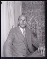 Oceanographer William Beebe seated in front of a tapestry, Los Angeles, 1932