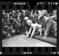 Actress Ali MacGraw placing her hand prints in cement at Chinese Theater in Hollywood, Calif., 1972