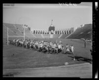 Western State Conference college football players running across Los Angeles Coliseum field, 1950