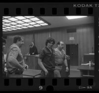 Richard Ramirez (aka The Night Stalker) smiling at camera as he is escorted by sheriffs from court in Los Angeles, Calif., 1986