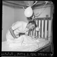 Male nurse, Lynn Loufek, attending to infant at Children's Hospital Los Angeles, Calif., 1971