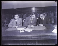 Defendents Dave Getzoff and Ben Getzoff with defense attorney Al McDonald in a courtroom, Los Angeles, 1929