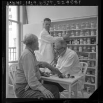 Dr. W. W. Altig examines patient at the Union Rescue Mission medical clinic in Los Angeles, Calif., 1964