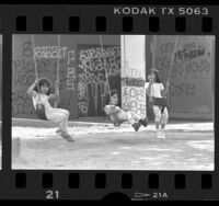 Youngsters on swings at graffiti covered park in South-Central Los Angeles, Calif., 1988