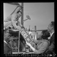 Myrlie Evers handing city worker Ted R. Aurand new Evers Ave. street sign in Compton, Calif., 1964