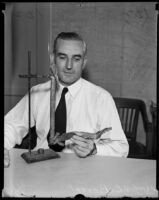 Chief V. E. Pierret, holding the remains of a homemade bomb, Los Angeles, 1935