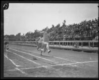 Charley Paddock leaping through finish line in USC shirt, Los Angeles, 1920s