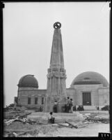 Astronomers Monument at the nearly completed Griffith Observatory, with 3 girls writing on the base with chalk, Los Angeles, circa 1934-1935