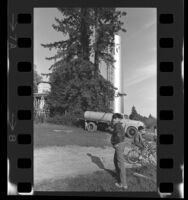 Boys riding bicycles past unused water storage tank on Kashia Indian Reservation, Stewarts Point (Calif.), 1970