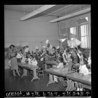 Elena Kunz covering her ears as third graders hurl papers in air on last day of school at Castelar Elementary School in Los Angeles, Calif., 1961
