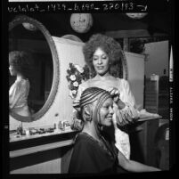 Hair stylist Cleo Jackson adding false braids to African American model in Los Angeles, Calif., 1972