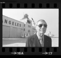 Henry Bakes standing before Mines Field airport tower as wrecking ball begins demolition in Los Angeles, Calif., 1974