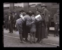 At train station, a soldier in uniform welcomed home by his wife and son, Los Angeles, 1919