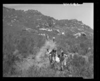 Krishna Venta (left) and Brother Paul of Fountain of the World Sect give aid in carrying one of the plane crash victims to ambulance, 1949