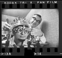 Researcher Derek Fender fitting apparatus for measuring brain waves on head of test subject at Caltech, 1974