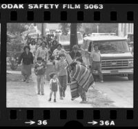 Ismael Cazarez wearing serape and playing flute leading protest of housing demolition in Pico-Union neighborhood in Los Angeles, Calif., 1980